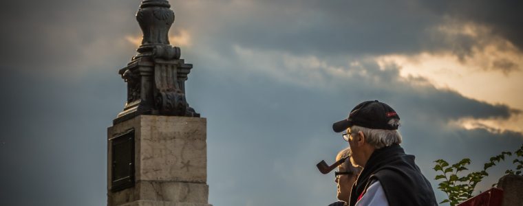 elderly couple sitting outside on a bench next to lamppost engaged in deep thought