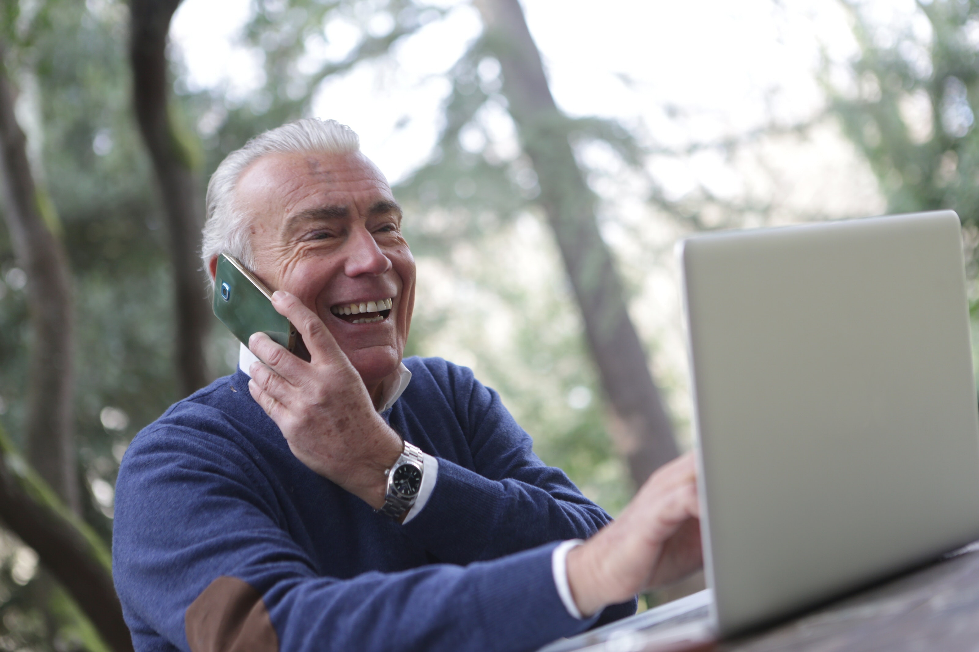 elderly man on phone and laptop receiving remote elder law services