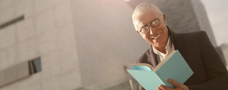 smiling elderly man reading outside