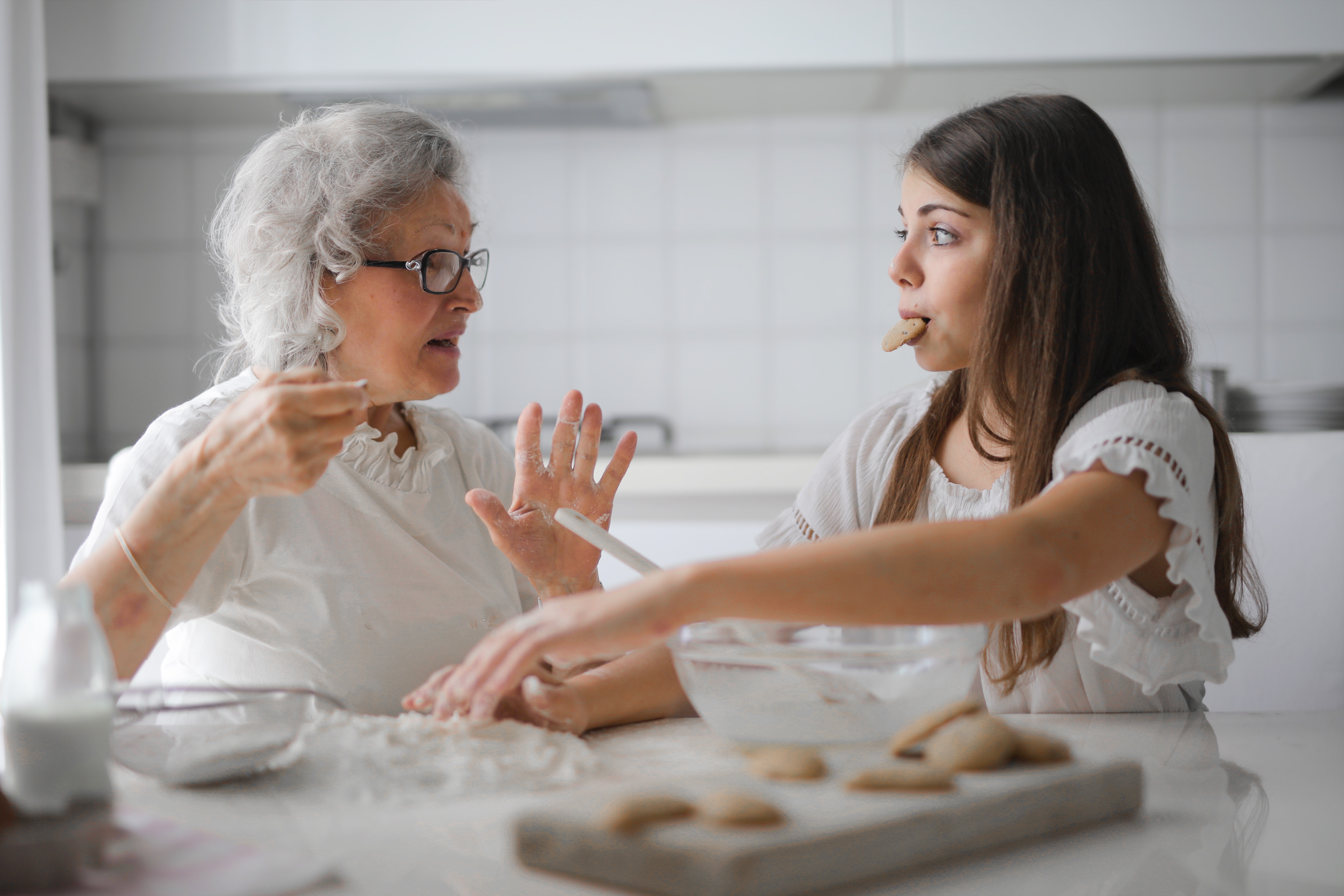 grandmother with granddaughter eating in kitchen