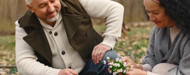 senior couple picking flowers among trees