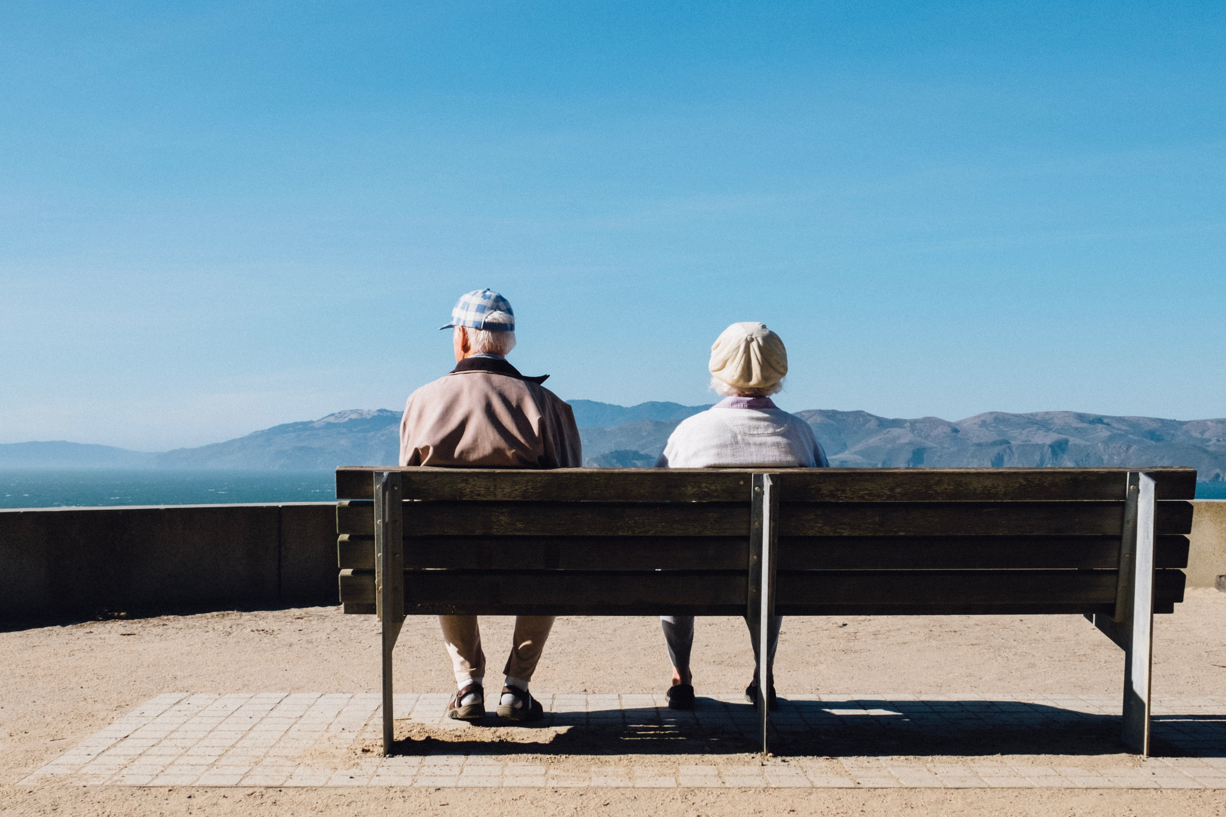 elderly couple sitting on bench with mountain view
