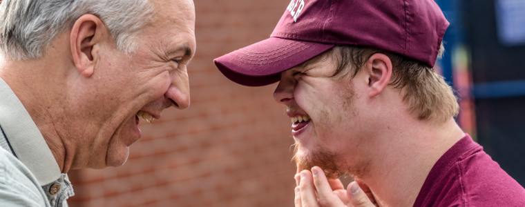 father smiling with disabled grandson