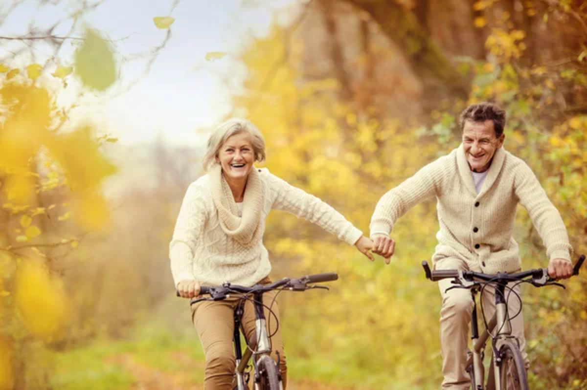 Senior couple bike riding among autumn trees
