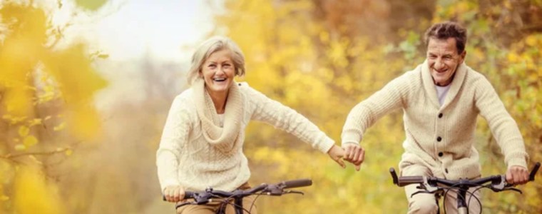 Senior couple bike riding among autumn trees