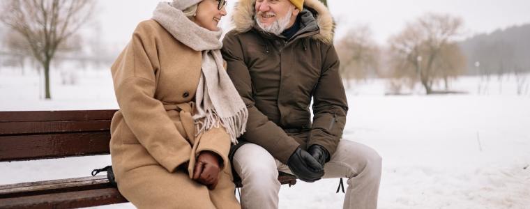 husband and wife sitting on bench in the snow