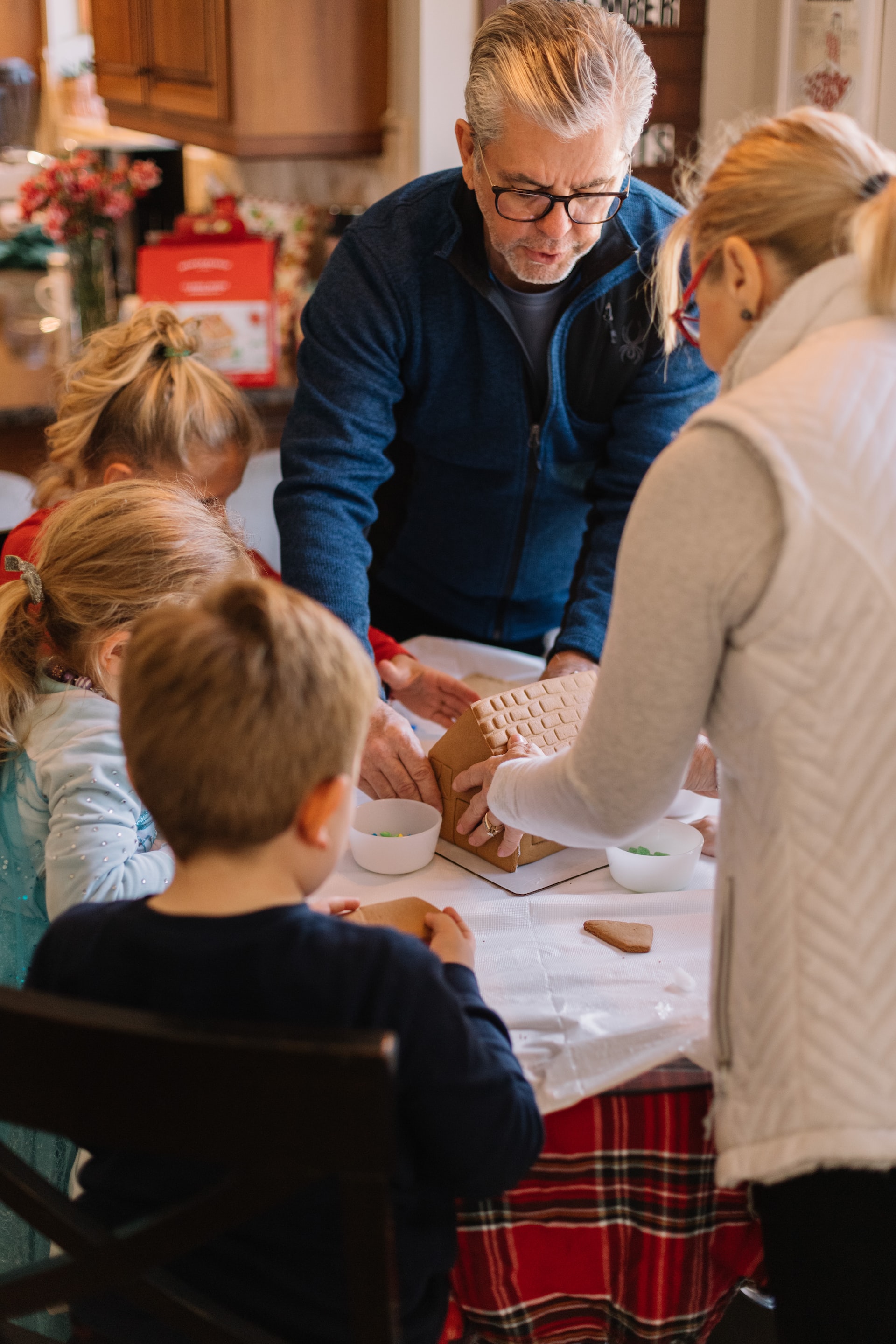 grandparents building a gingerbread house with their grandchildren