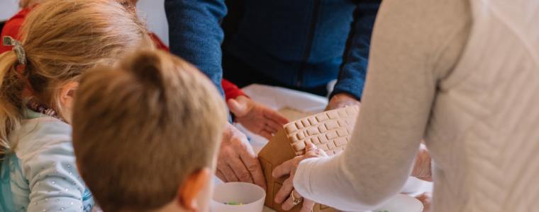 grandparents building a gingerbread house with their grandchildren