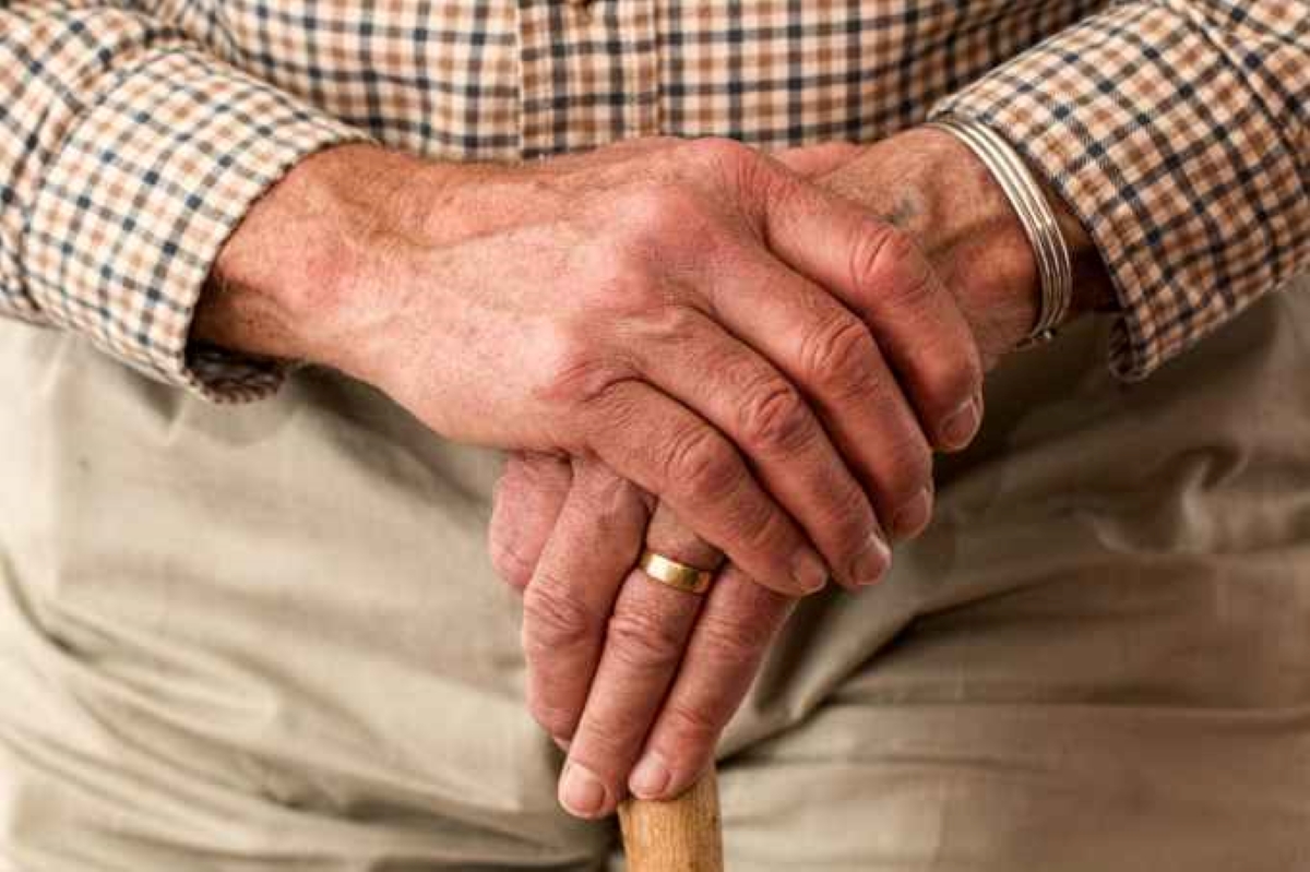 elderly hands resting on a cane