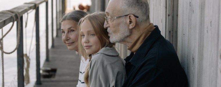 grandparents sitting on a dock with their granddaughter
