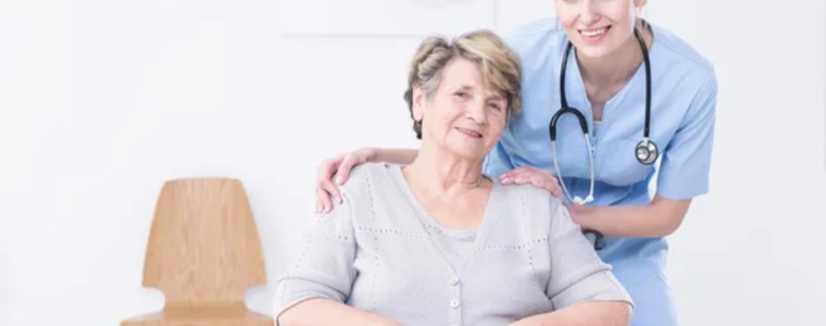 nurse with her arms around senior patient in a wheelchair