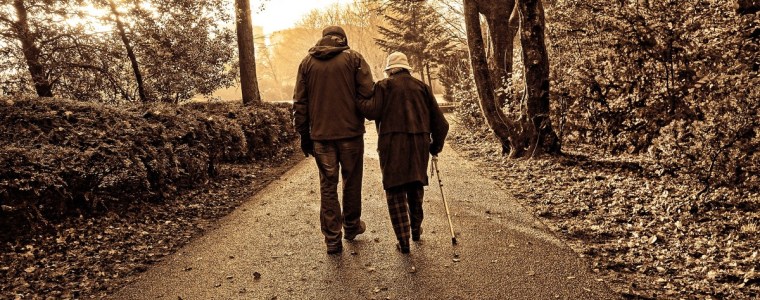 elderly couple walking along wooded path