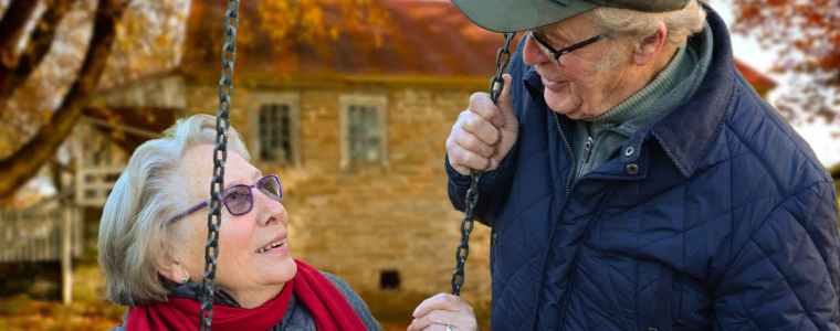elderly couple smiling on swings