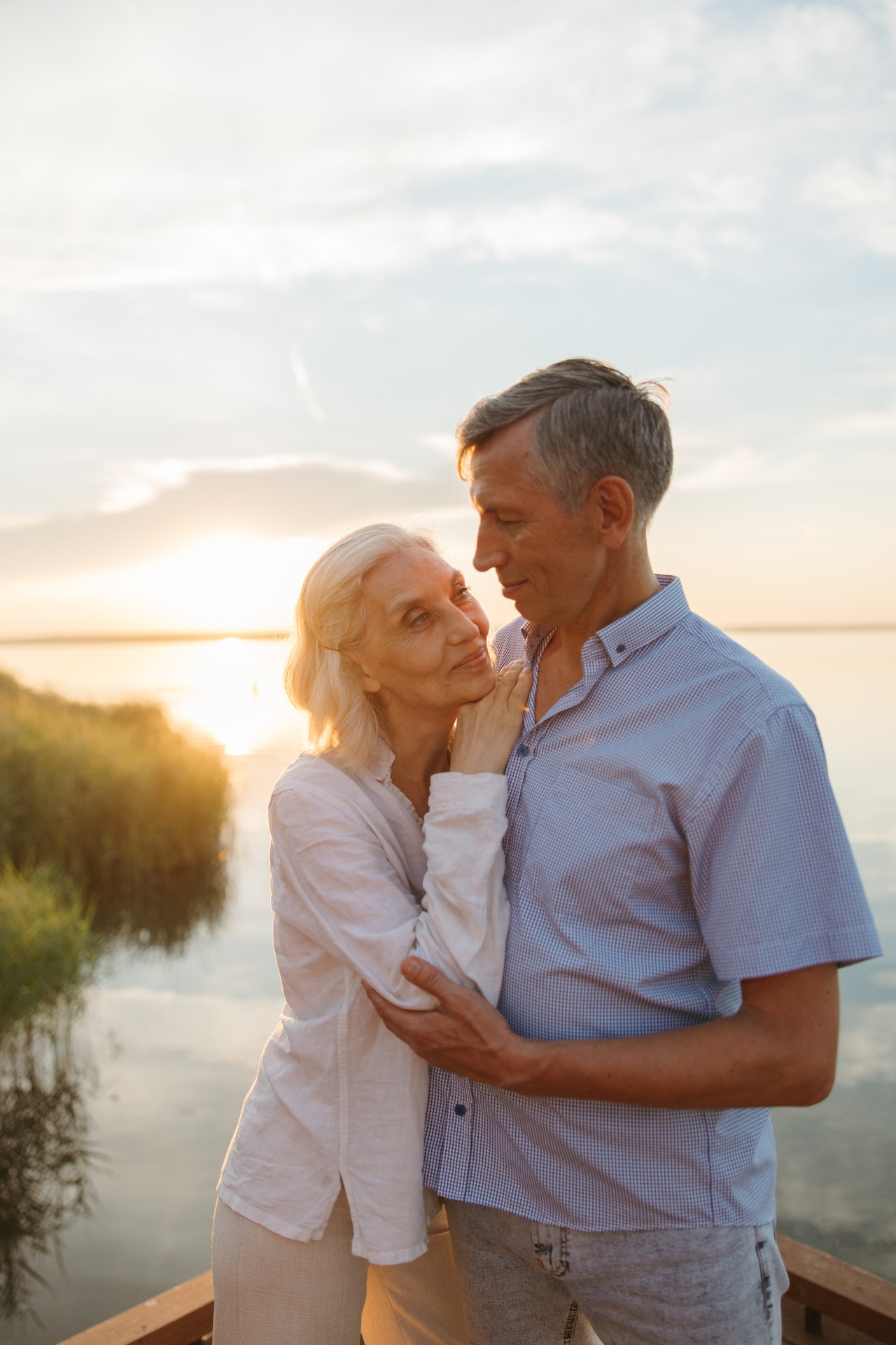 couple standing on deck next to lake