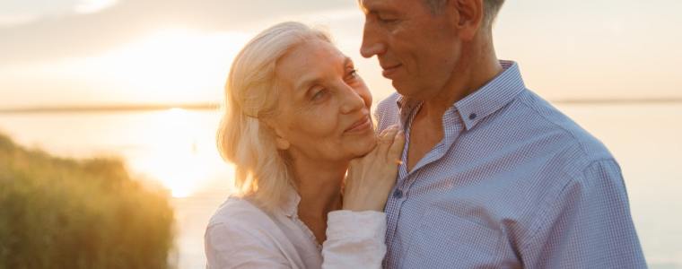 couple standing on deck next to lake